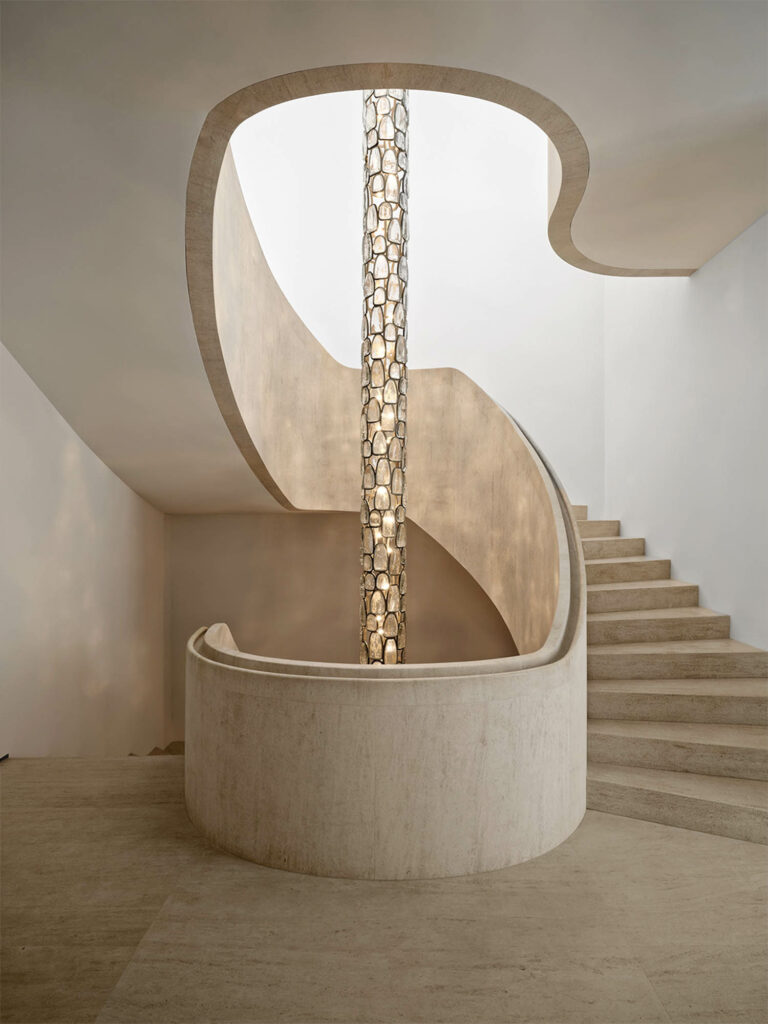a limestone staircase wraps around a pendant fixture
