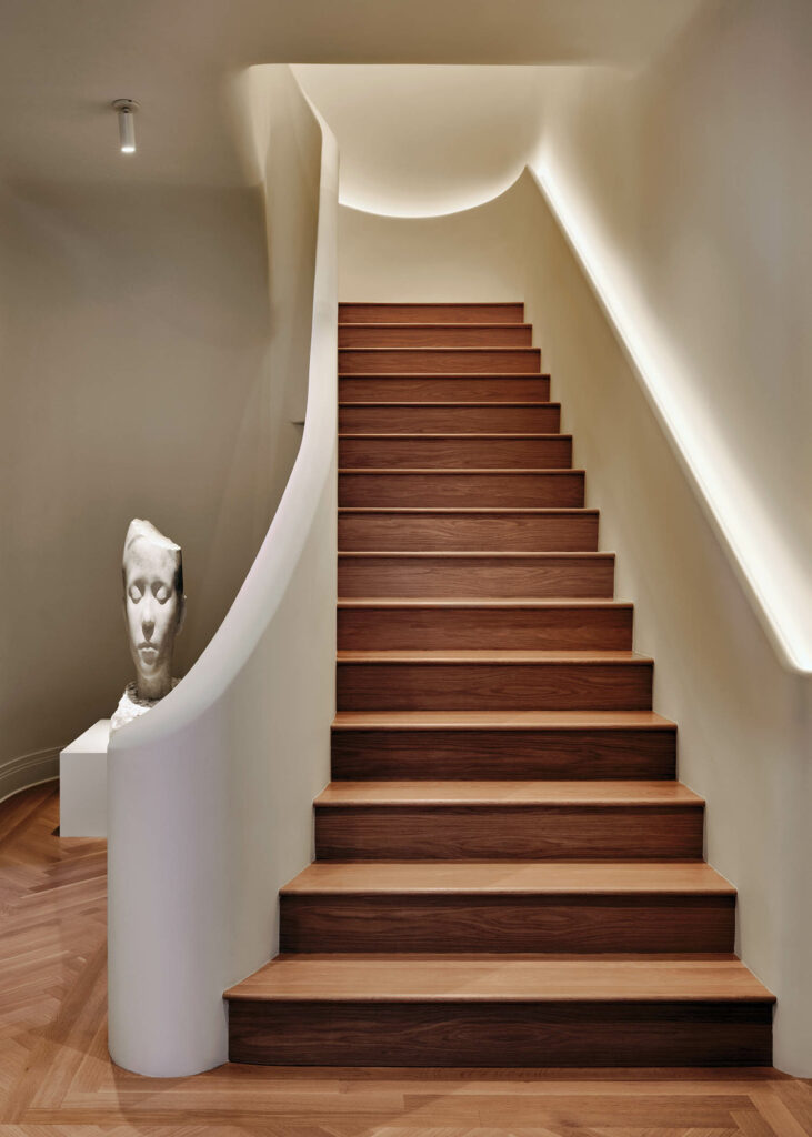 the staircase of a New York apartment flanked by a Jaume Plensa sculpture