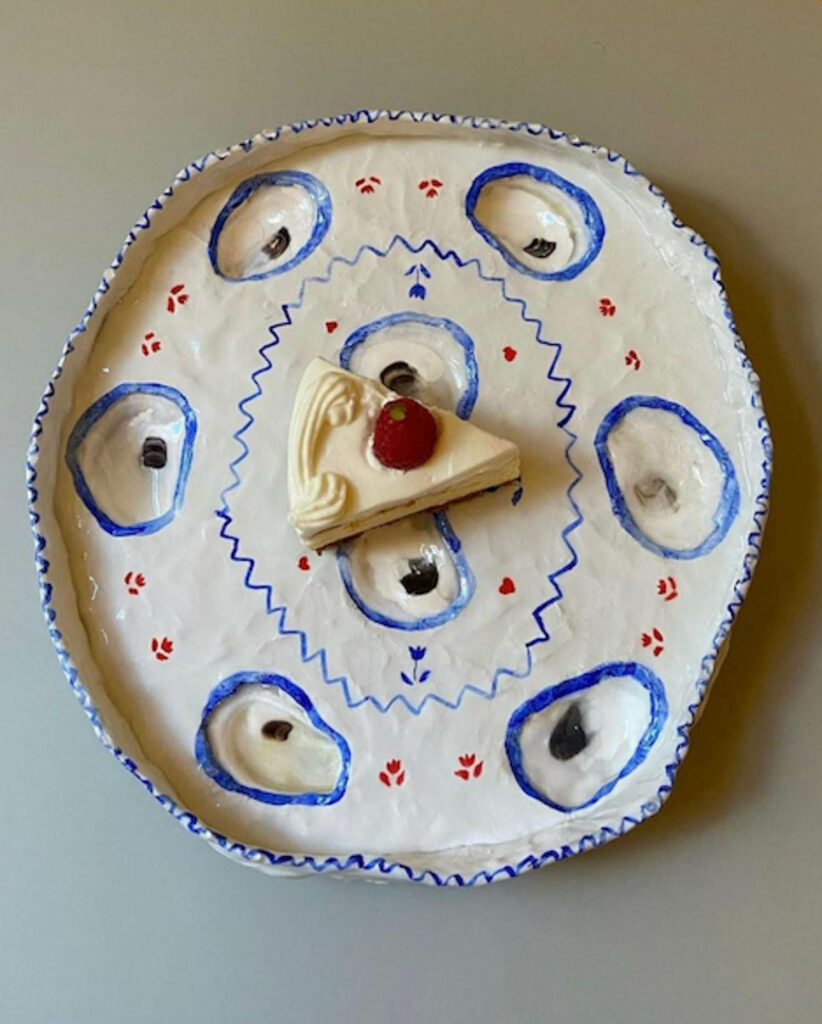 a piece of cake sits atop a white ceramic dish with blue and red details