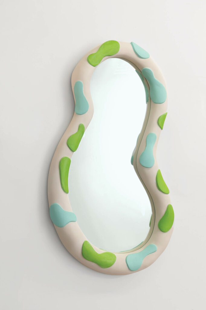 a curvy mirror with a white plaster border with green shapes