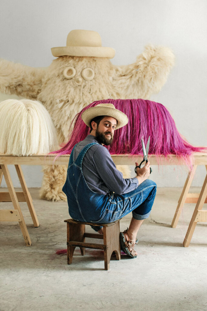 The designer in his Santo Domingo Tonahuixtla, Mexico, studio in 2018, working on a Pup bench covered in raw sisal fibers from the leaves of agave plants, the same material used for Monster, part of a larger installation, in the background.