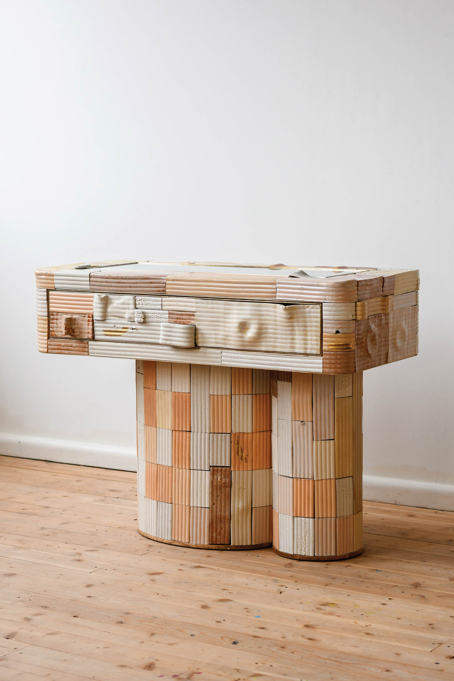 a patchwork console clad in pale orange stone­ware tiles
