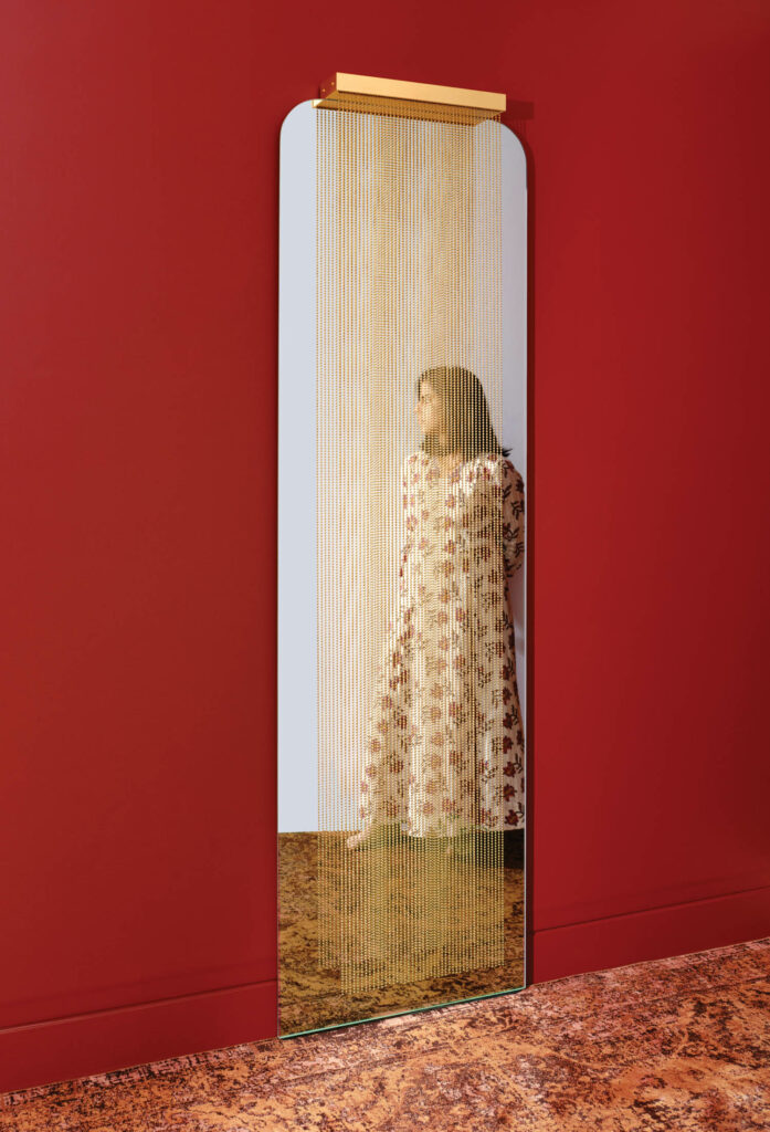 a woman standing in a mirror surrounded by red walls