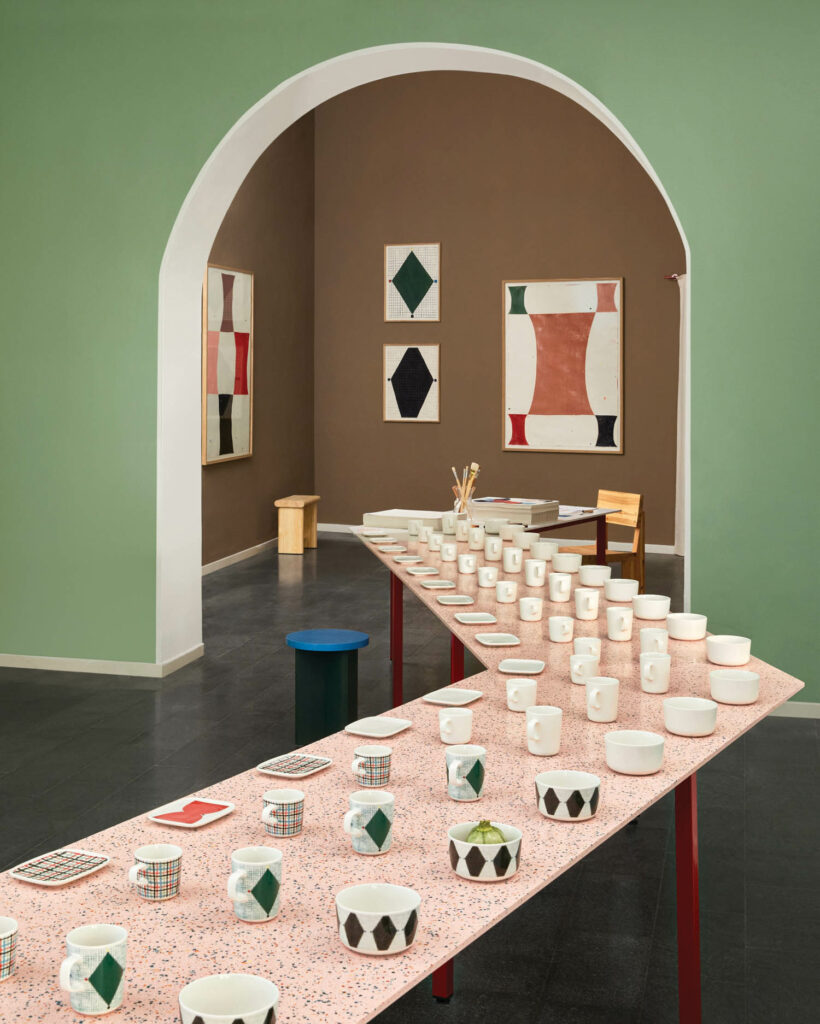 a long light pink table dotted with ceramic mugs and plates