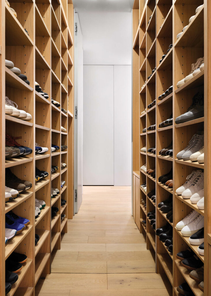 Floor-to-ceiling shelves in the entry’s mirror-backed shoe closet