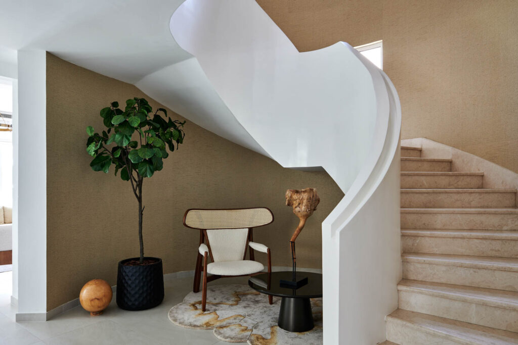 a white winding staircase with a white armchair and sculpture beneath it
