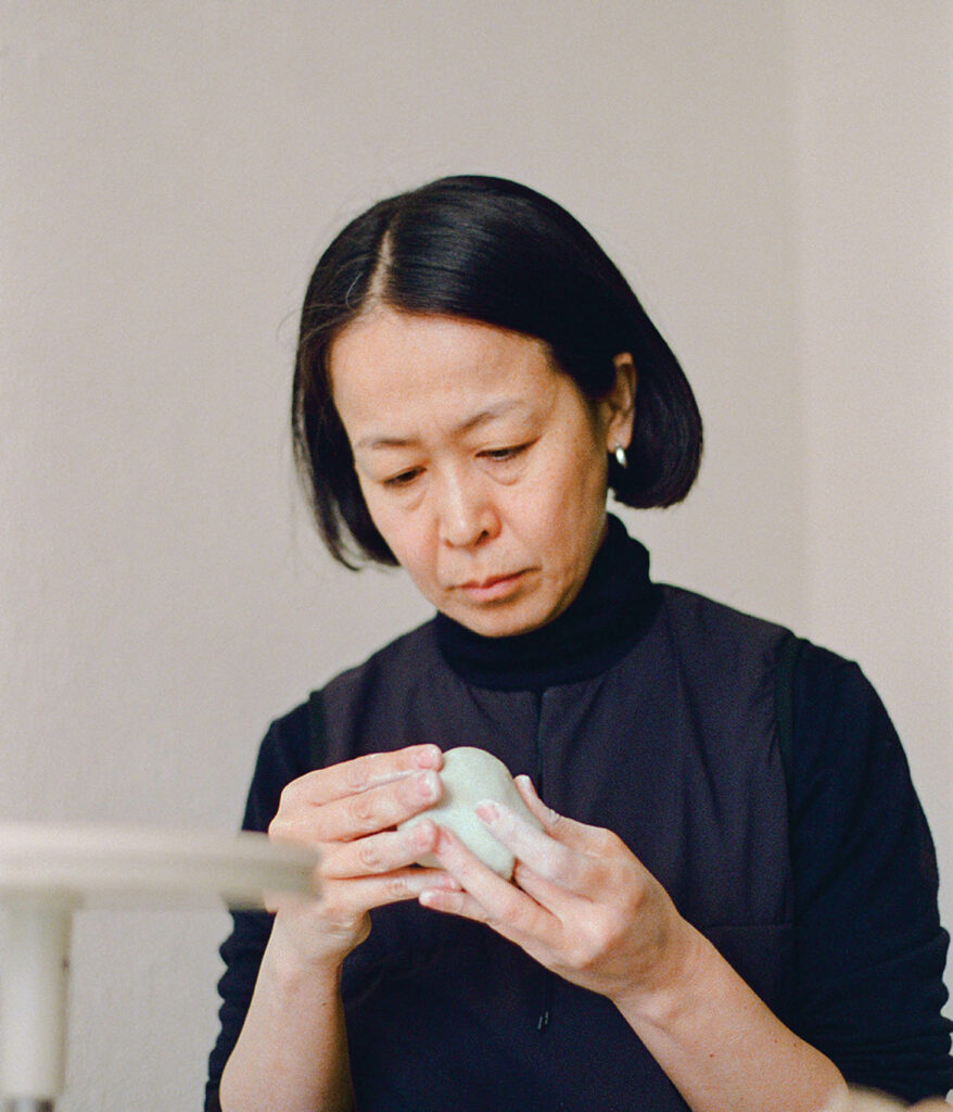 a woman in a black turtleneck holding a fixture