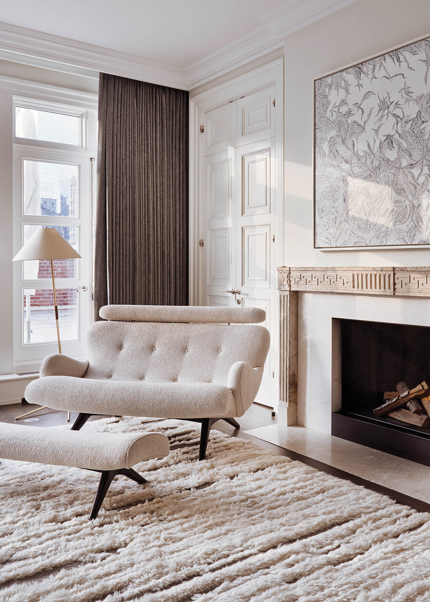 a white love seat and ottoman in front of a fireplace