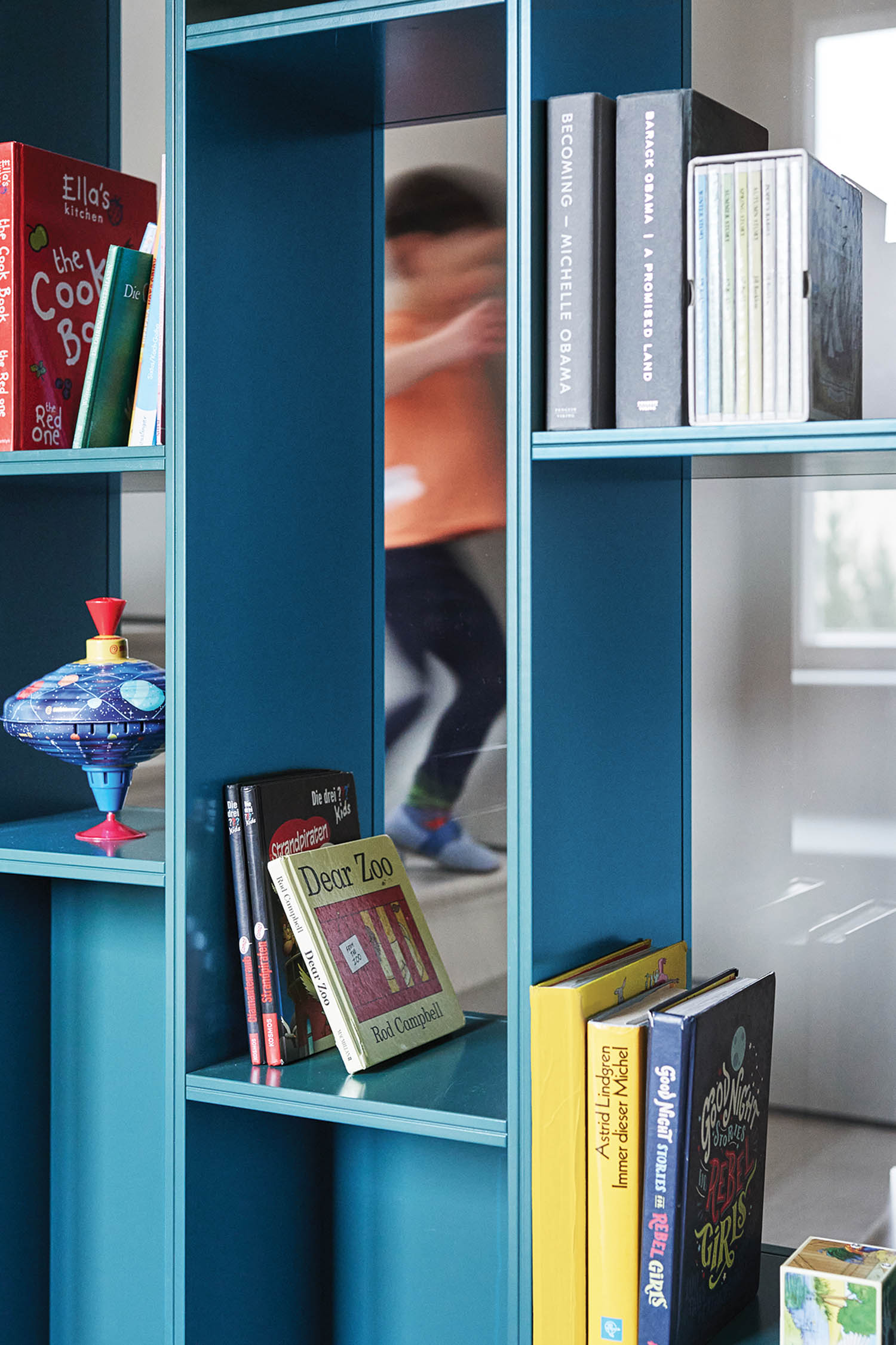 blue shelving with children's books and toys in it