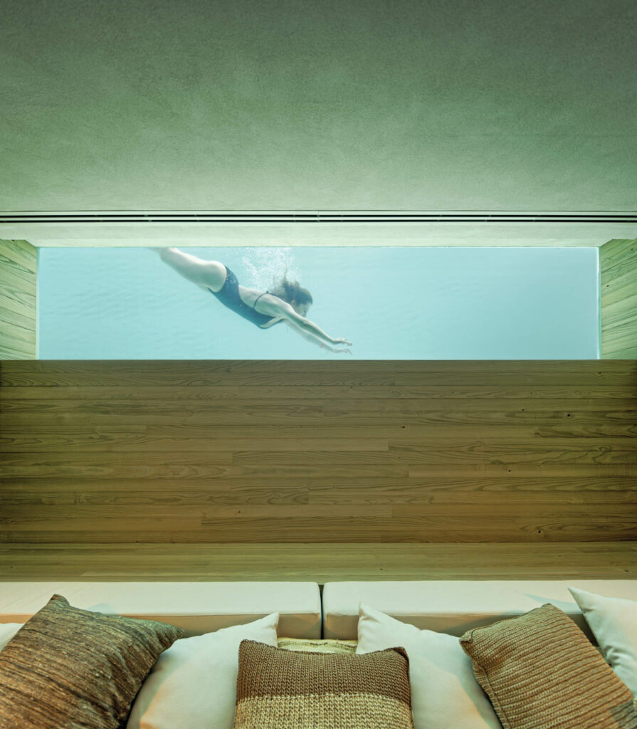 a lounge outside the sauna offers a peek into the glass-sided swimming pool outside