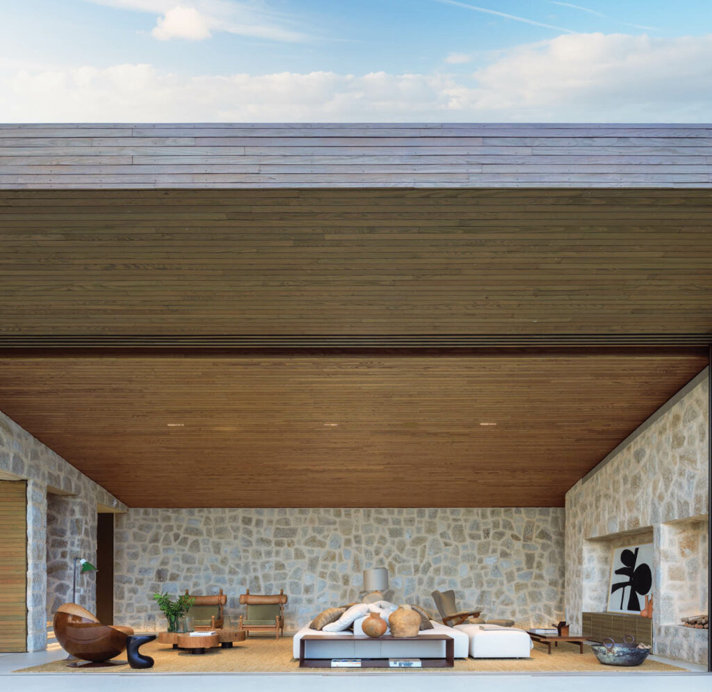 a pine ceiling above stone walls in the living room of a Brazilian home
