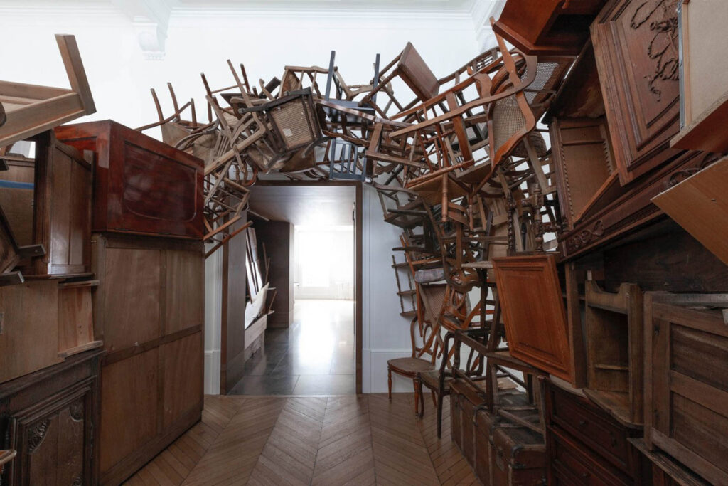 an arch of wooden chairs over a doorway