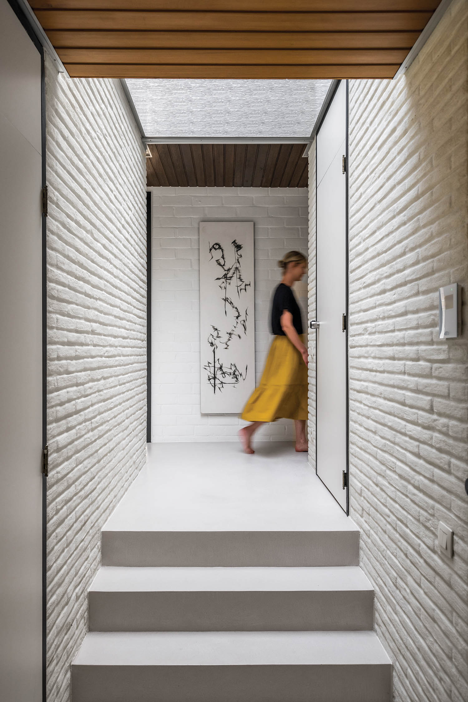 a woman walks through the hallway with whitewashed bricks
