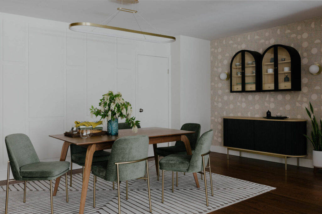 The dining room with a minimalist wood table and velvet green chairs