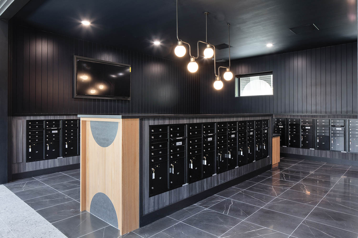 a series of lockers in a room with pendant lights and dark gray walls