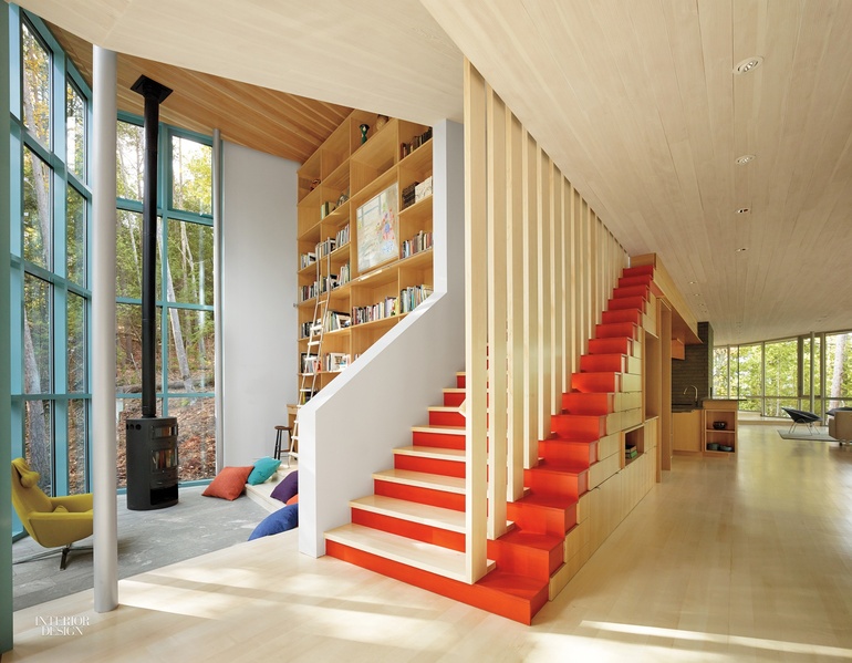 A stairwell with red steps that give way to slats of light wood features a vaulted ceiling